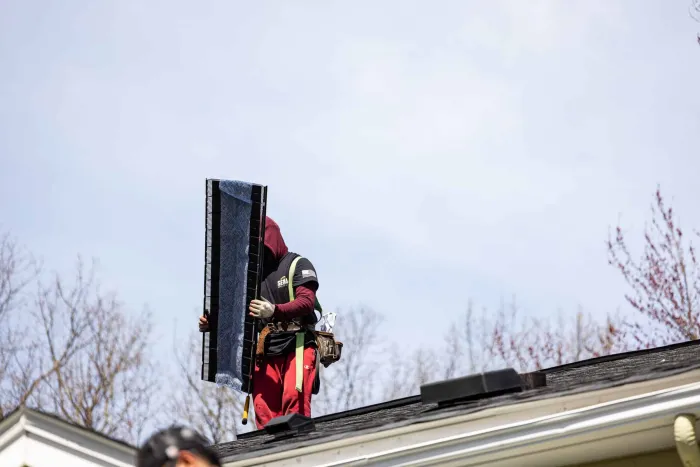 Senco crew member carrying a section of ridge vent across a roof in Tewksbury, MA