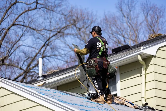 Senco crew member working a roofline above seamless white gutters on a home in Tewksbury, MA